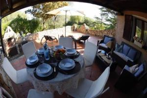 - une table à manger avec des chaises blanches et un parasol sur la terrasse dans l'établissement TARA Village, à Porto Pollo