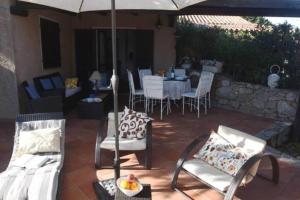 une terrasse avec une table, des chaises et un parasol dans l'établissement TARA Village, à Porto Pollo