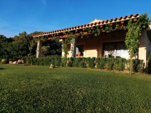 une maison avec une pelouse verte devant elle dans l'établissement Agriturismo Fioredda, à Aglientu