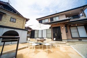 een terras met een tafel, stoelen en een parasol bij Awaji egaosakuie tonouchi in Awaji