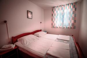 sypialnia z dużym łóżkiem z białą pościelą i oknem w obiekcie Apartments Mia w mieście Pag