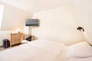 a white bedroom with a bed and a chair at maakt Apartments in Stralsund