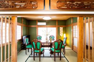 ein Esszimmer mit grünen Wänden sowie einem Tisch und Stühlen in der Unterkunft Awaji egaosakuie tonouchi in Awaji
