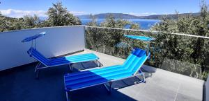 two blue chairs and an umbrella on a balcony at Sea-esta 1 in Valun
