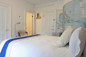 a bedroom with a large white bed with a map on the wall at The Hotel Marblehead in Marblehead