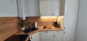 a kitchen with white cabinets and a sink and a plate of fruit at Apartament Łąkowa in Polanica-Zdrój
