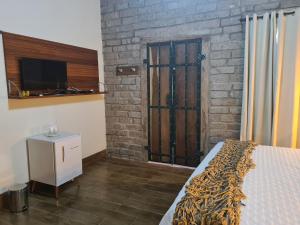a bedroom with a bed and a tv and a brick wall at Bosque São Francisco in Chapada dos Guimarães