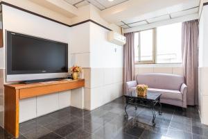uma sala de estar com uma televisão de ecrã plano na parede em Yi Pin Business Hotel em Taoyuan