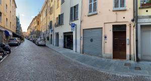 una calle adoquinada con coches y edificios aparcados en Appartamento Frida, en Parma