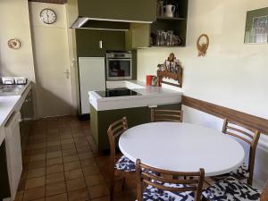een keuken met een witte tafel en een tafel en stoelen bij Le Grand Praz in Saint-Jorioz