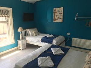 2 camas en una habitación con paredes azules en The Glenroy Guest House, en Blackpool