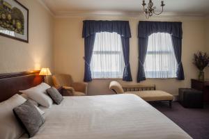 a hotel room with a large bed and two windows at OYO Devonshire Park Hotel in Eastbourne
