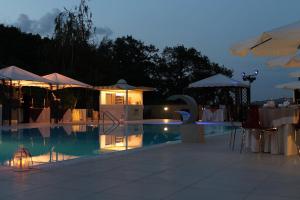 a swimming pool with tables and umbrellas at night at Sotto Il Cielo Hotel in Pignola