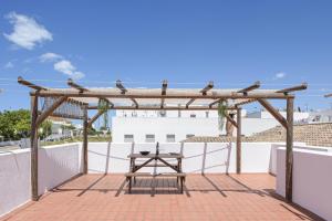 pérgola de madera con mesa en el patio en Casa Ainhoa, en Conil de la Frontera