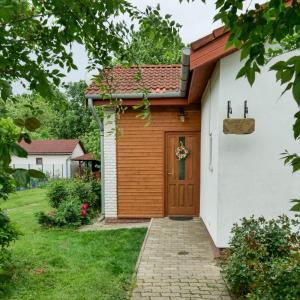 uma casa com uma porta de madeira num quintal em Cseresznyés Apartman em Berekfürdő