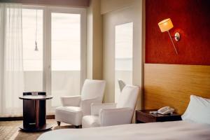 Habitación de hotel con sillas blancas, cama y mesa en Rayentray Puerto Madryn en Puerto Madryn