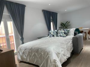 um quarto com uma cama branca e cortinas azuis em Apartamento Nebro Estrella em Cádiz