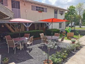 a patio with tables and chairs and umbrellas at Chambres dhôtes Logette in Consenvoye