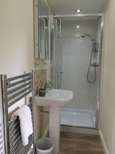 een witte badkamer met een wastafel en een douche bij Forest View Guesthouse, Kinlochleven WHW in Kinlochmore