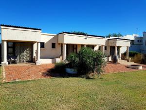 ein weißes Haus mit Rasen davor in der Unterkunft CHEETAH MANOR #3 in Bloemfontein