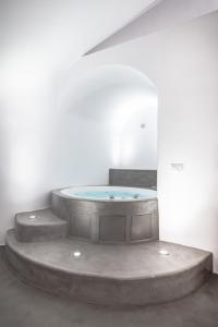 - un bain à remous dans une chambre blanche avec des escaliers dans l'établissement Deep Earth Villas, à Éxo Goniá