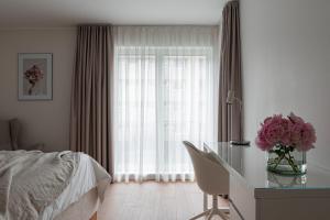 a bedroom with a bed and a desk with a vase of flowers at Modern City Center Apartment in Tallinn