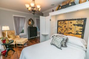 a bedroom with a white bed and a chair at Riverside Gables Bed and Breakfast in Berea