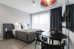 ApartPark Baltic Home في سفينويتشي: غرفة نوم بسرير وطاولة مع كراسي