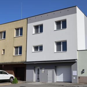 a white building with a car parked in front of it at Apartmány U koupaliště in Znojmo