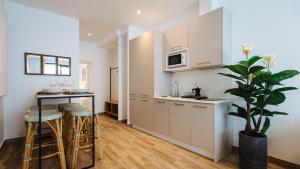 a kitchen with white cabinets and a table and stools at Magno Apartments Alameda 1851 - Shared jacuzzi in Seville