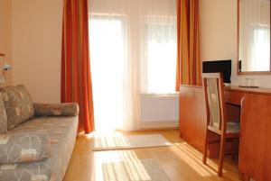 a living room with a couch and a desk at Stan és Panzió in Balatonalmádi