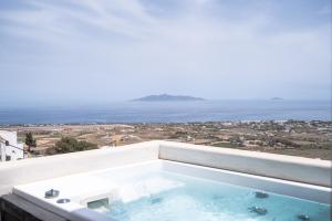 a hot tub on a balcony with the ocean in the background at Deep Earth Villas in Éxo Goniá