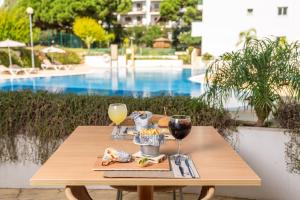 una mesa de madera con copas de vino y comida. en AP Victoria Sports & Beach, en Albufeira