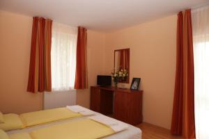 a bedroom with a bed and a window with red curtains at Stan és Panzió in Balatonalmádi +61 photos