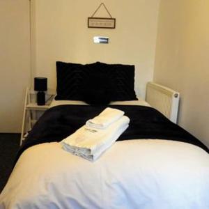 Kings Arms Hotel في هولسوورثي: غرفة نوم بسرير مع شراشف بيضاء ومخدة سوداء