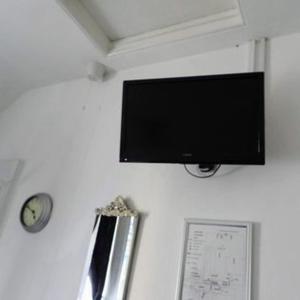 einen Flachbild-TV, der an einer Wand mit einer Uhr hängt in der Unterkunft Kings Arms Hotel in Holsworthy