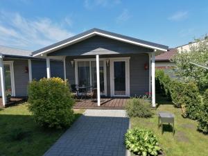 a house with a deck with a table and an umbrella at Vila Laima in Šventoji