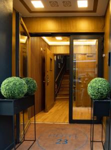a hallway with two potted plants in front of a door at Hôtel Le 23 in Clichy