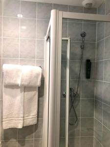 a bathroom with a shower with white towels at Hôtel Le 23 in Clichy