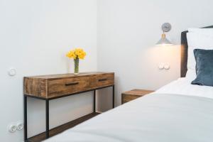 Un dormitorio con una cama y una mesa con un jarrón encima. en Berchy Apartment 1, en Liepāja