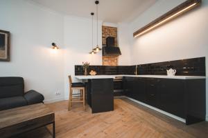 Una cocina con gabinetes negros y una encimera blanca. en Berchy Apartment 1, en Liepāja 10 fotos más