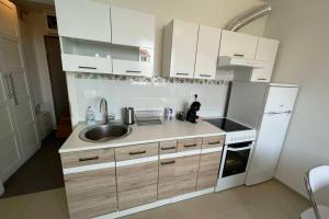 La cuisine est équipée de placards blancs, d'un évier et d'un réfrigérateur. dans l'établissement Apartment Gema - One bedroom apartment, à Izola
