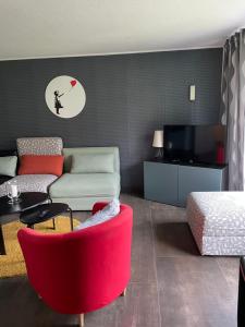 Appartement Max في كلاوستال-زيلرفيلد: غرفة معيشة مع كرسي احمر واريكة