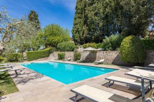 a swimming pool in a yard with two lounge chairs at Il Giardino Inglese in Lucignano