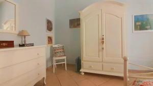 a bedroom with a white cabinet and a chair at Casa Vacanze "Donna Manu', tra Stazione Centrale, Metro e Aeroporto TURISMO CULTURALE in Naples