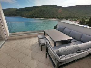 a couch and a table on a balcony with a view of the water at Apartment More 13 in Rabac