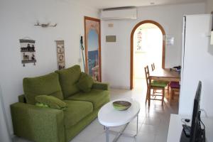 un soggiorno con un divano verde e un tavolo di Portobello Verena a Port de Pollença