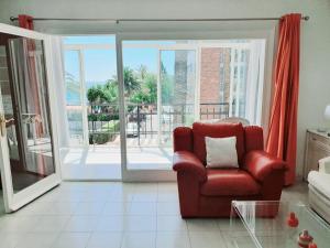 een woonkamer met een rode stoel en een balkon bij Urbanizacion La Roca Estudio in Torremolinos