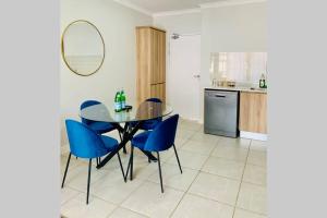 a dining room with a glass table and blue chairs at Stay Upmarket at The Blyde in Boschkop