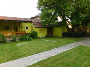 een geel huis met een tuin en een boom bij Pensiunea Bunea in Haţeg